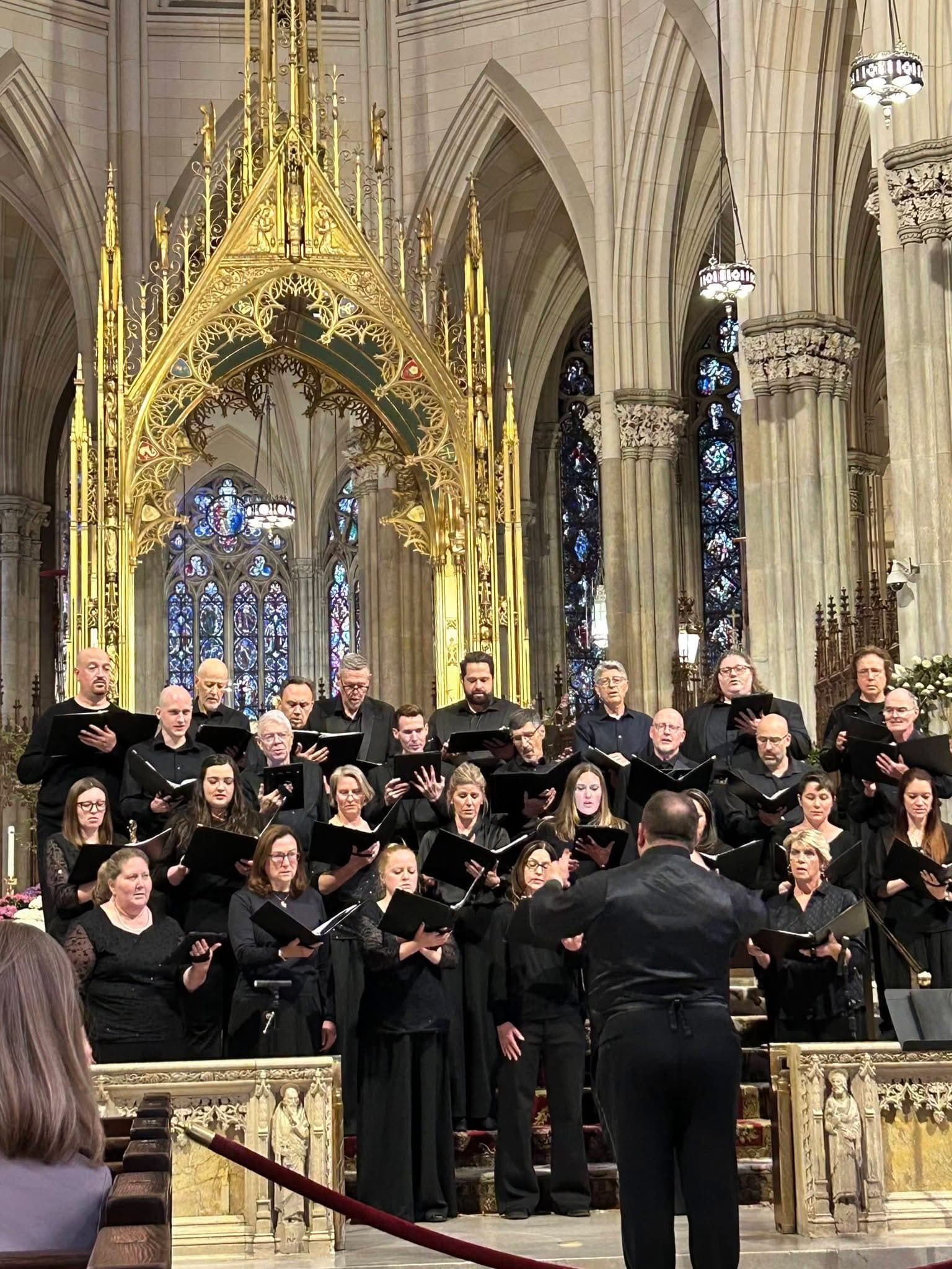 The Soli Chamber Choir singing from black folders beneath a gilded altar canopy in a Gothic cathedral